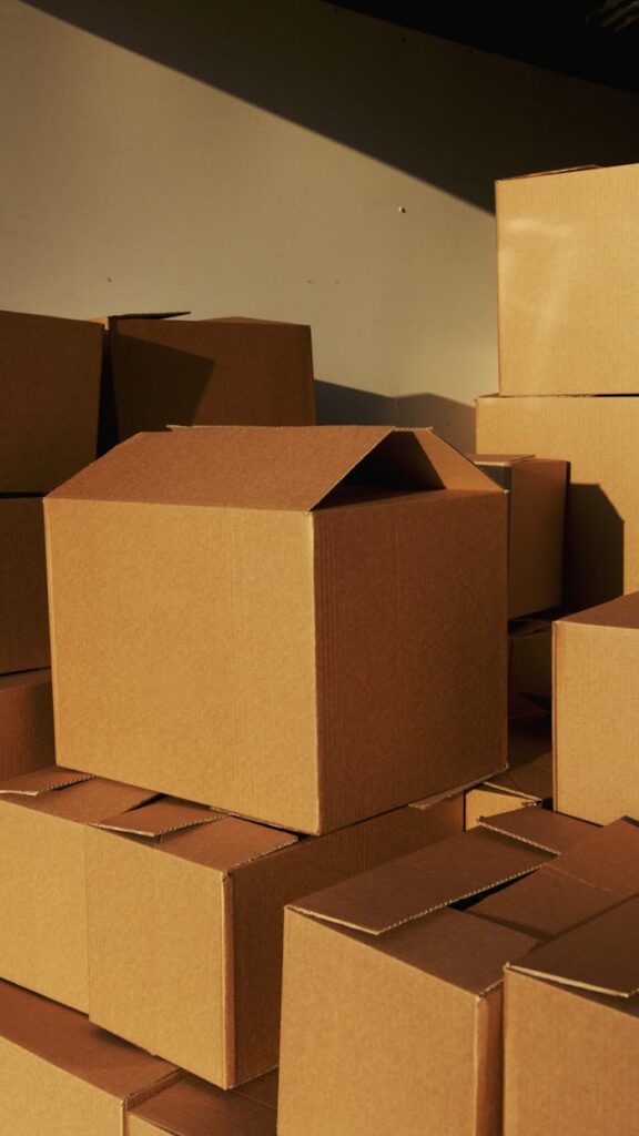 pexels-photo-5025503-1 Stacked cardboard boxes ready for shipping or storage in a warehouse setting.